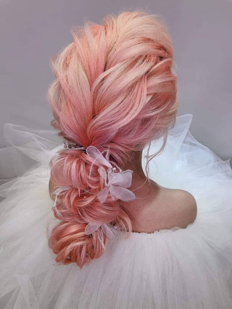 Person with long pink braided hair styled with ribbons, wearing a white tulle top, viewed from behind