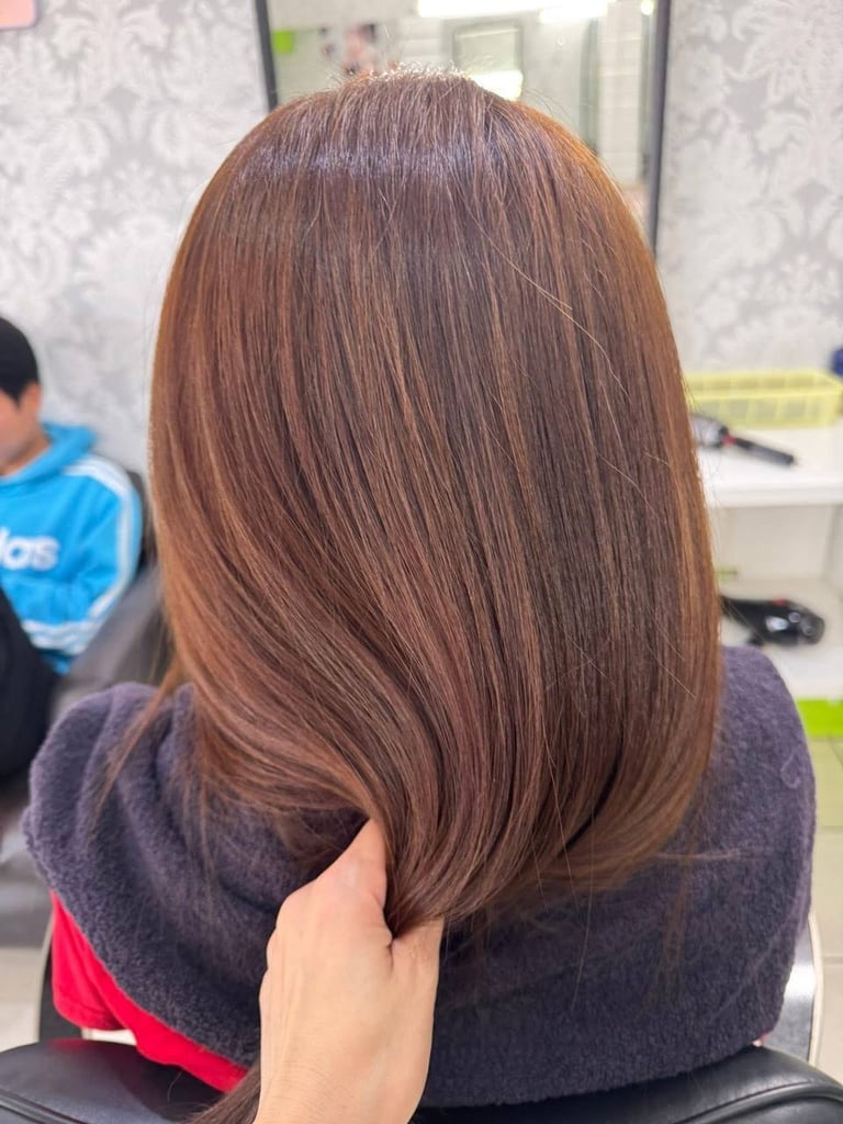 Back view of person with long, straight medium brown hair in a salon setting