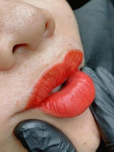 Close-up of womans face with bold red lipstick, dark eyeshadow, and profile view showing nose and lips