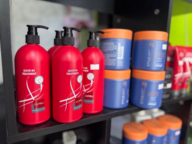 Red hair treatment bottles with black pump dispensers and blue/orange containers displayed on a shelf in a salon