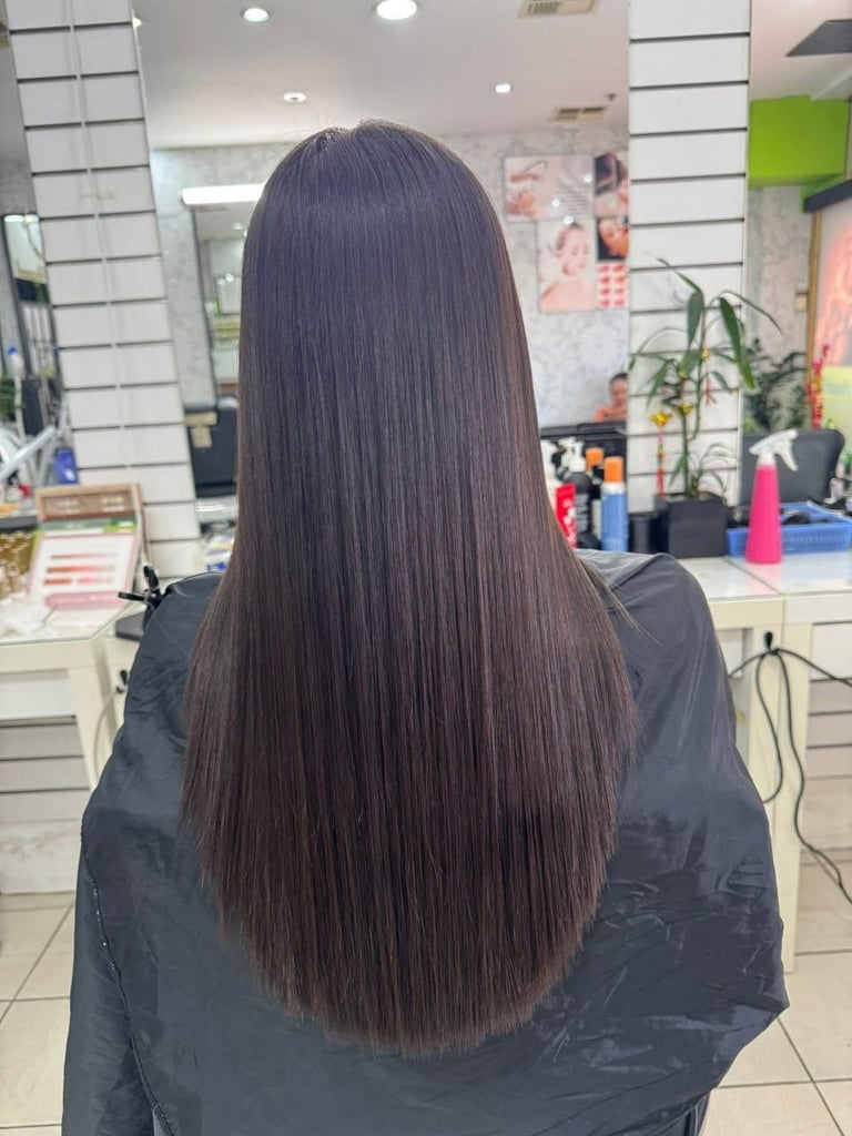 Woman with long dark straight hair shown from behind in a salon setting
