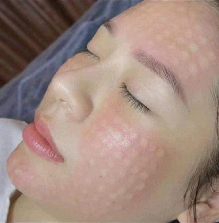Close-up of a womans face with eyes closed and head tilted back, showing relaxed expression and light makeup